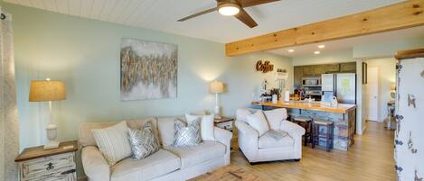 A living room with a sofa, a wooden coffee table, and a ceiling fan.