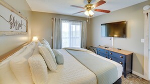 A bedroom with a bed, a ceiling fan, a TV, a dresser, and a window with curtains. - Unwind Fireside: Ozark Mtn Condo w/ Resort Perks! (Branson West)