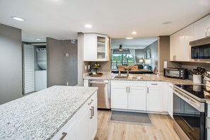 A modern kitchen with granite countertops, white cabinets, a built-in oven, and a microwave.