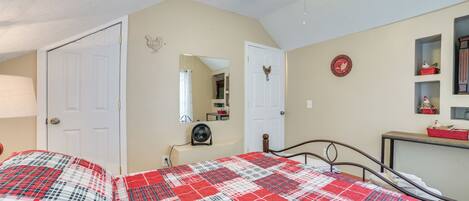 Une chambre à coucher avec un lit, un ventilateur de plafond, un miroir et une commode.