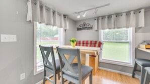 A dining area with a wooden table, grey upholstered chairs, and a red and white striped sofa. - Visit Fife Lake & Traverse Bay! Farmhouse Hideaway (Fife Lake)