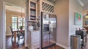 A kitchen with a stainless steel refrigerator, a dining table with chairs, and a chandelier. - Lake LBJ Waterfront Vacation Rental! (Marble Falls)