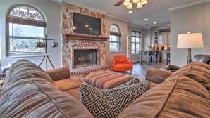 A living room with a stone fireplace, leather sofas, and a television mounted on the wall. - Lake LBJ Waterfront Vacation Rental! (Marble Falls)