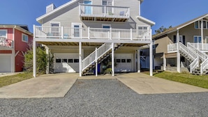 A two-story house with a balcony, a garage, and a staircase leading to the second floor. - Ocean Isle Beach Home w/ Canal Views! (Ocean Isle Beach)