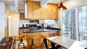 A modern kitchen with wooden cabinets, a large island, and a dining area with a bench and stools.