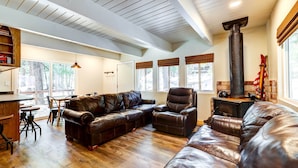 A spacious living room with a large leather sofa, a fireplace, and a dining area with a wooden table and chairs.
