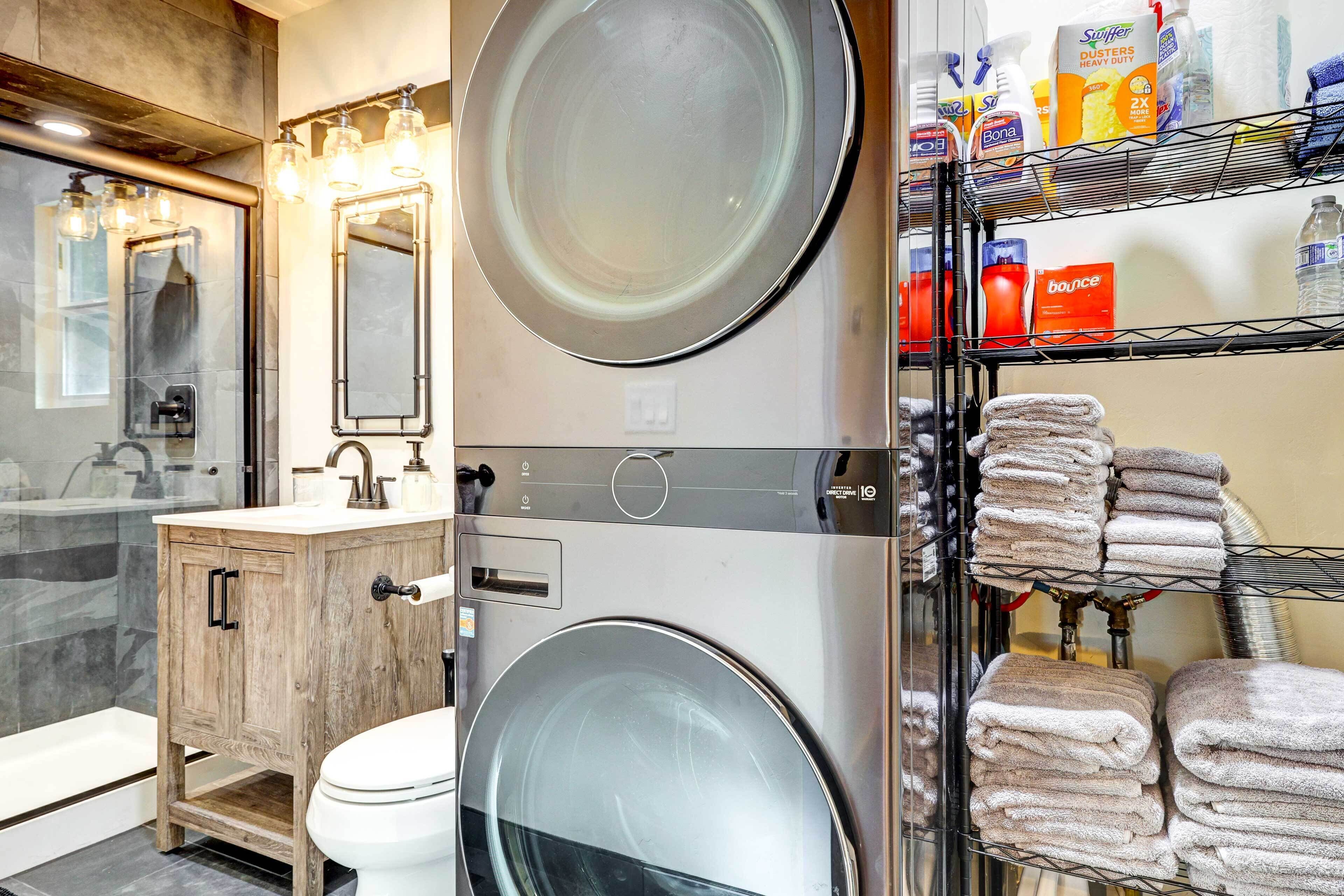 Une salle de bain moderne équipée d’un lave-linge et d’un sèche-linge intégrés, d’un meuble-lavabo en bois et d’une étagère pour les serviettes.