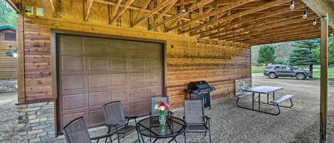 A covered patio area with a wooden ceiling, a large garage door, and a picnic table with chairs.