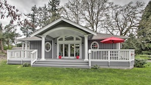 A two-story house with a covered porch, a red umbrella, and a well-maintained lawn. - Contemporary Tacoma Cottage w/ Deck & Pond! (Tacoma)