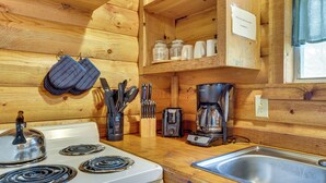 A wooden cabin kitchen with a stove, sink, and various utensils. - Cedar Falls Cabin: Nestled by Honey Creek (Davis)