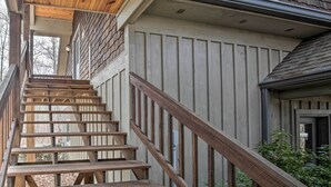 Una escalera de madera que lleva a una terraza en el segundo piso, con vistas de los alrededores.