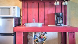 A kitchenette with a microwave, refrigerator, coffee maker, and a small sink.