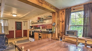 A rustic kitchen with wooden beams, a large wooden table, and a window with curtains. - Pet-friendly Roxbury Farmhouse on 350 Acres! (Roxbury)