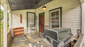 A porch with a wooden bench, a green door, and a grill. - Pet-friendly Roxbury Farmhouse on 350 Acres! (Roxbury)