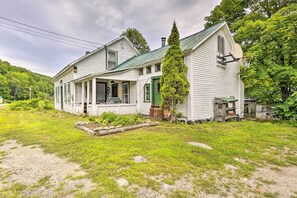 A two-story white house with a green roof, a porch, and a basketball hoop. - Pet-friendly Roxbury Farmhouse on 350 Acres! (Roxbury)