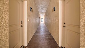 Un largo pasillo estrecho con puertas blancas a ambos lados y suelo de madera.