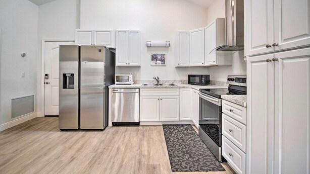 Una cocina moderna con armarios blancos, electrodomésticos de acero inoxidable y suelo de madera.