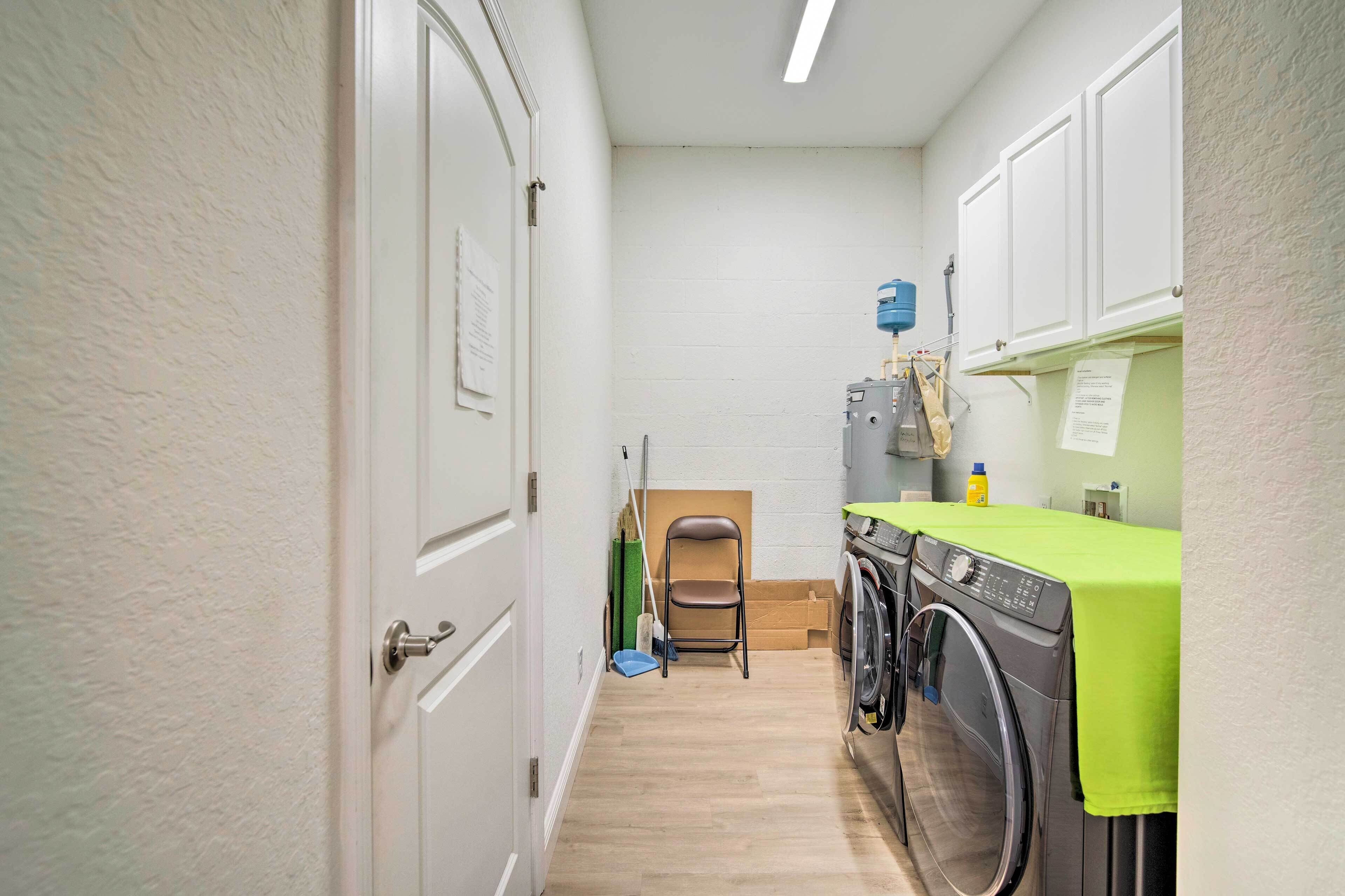 A laundry room with a washing machine, a folding chair, and a mop.