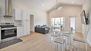 Una cocina amplia con electrodomésticos modernos, un comedor con mesa de vidrio y un sofá gris en la sala de estar.