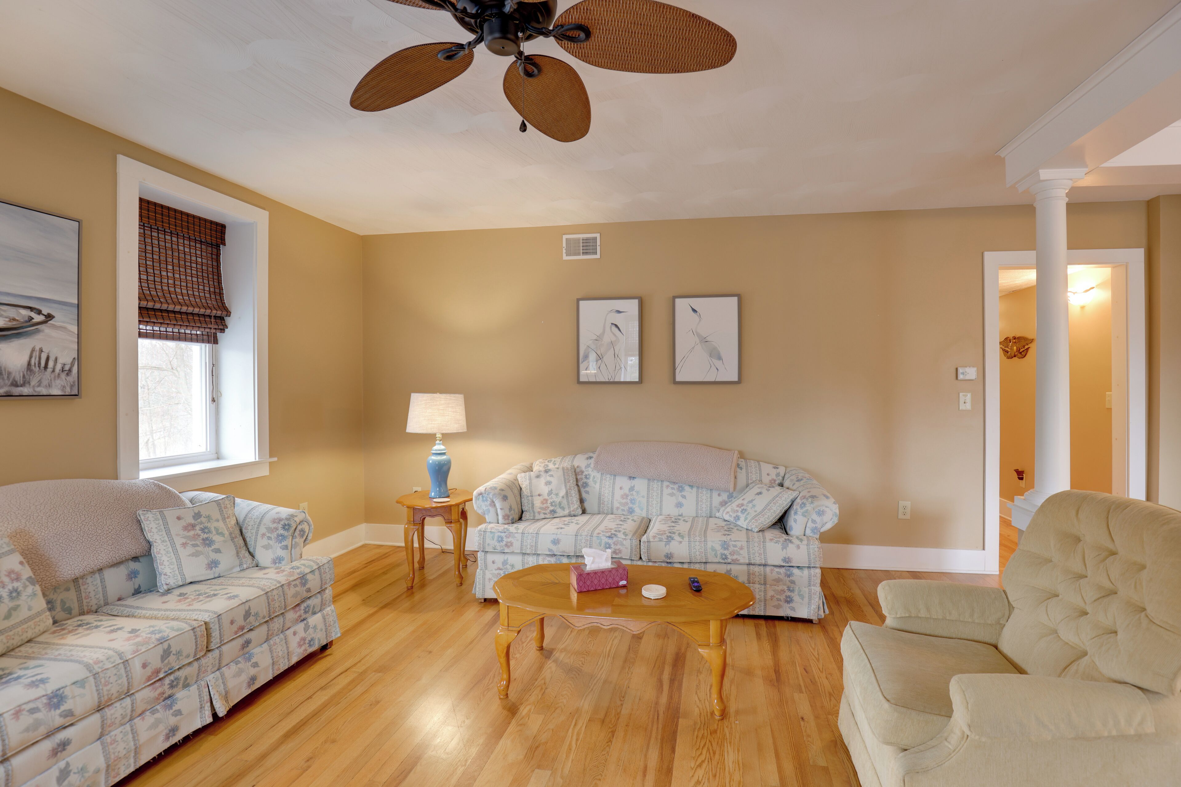 A living room with a sofa, armchair, coffee table, and a ceiling fan.