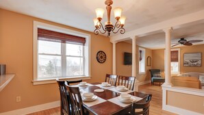 A dining area with a wooden table set for four, surrounded by chairs, a chandelier, and a window with blinds. - Finger Lakes Retreat: 3 Mi to Seneca & Keuka Lake (Himrod)
