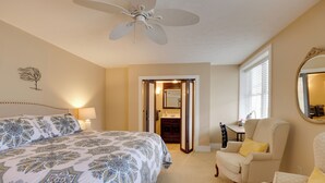 A bedroom with a large bed, a chair, a ceiling fan, a mirror, and a door leading to a bathroom. - Finger Lakes Retreat: 3 Mi to Seneca & Keuka Lake (Himrod)