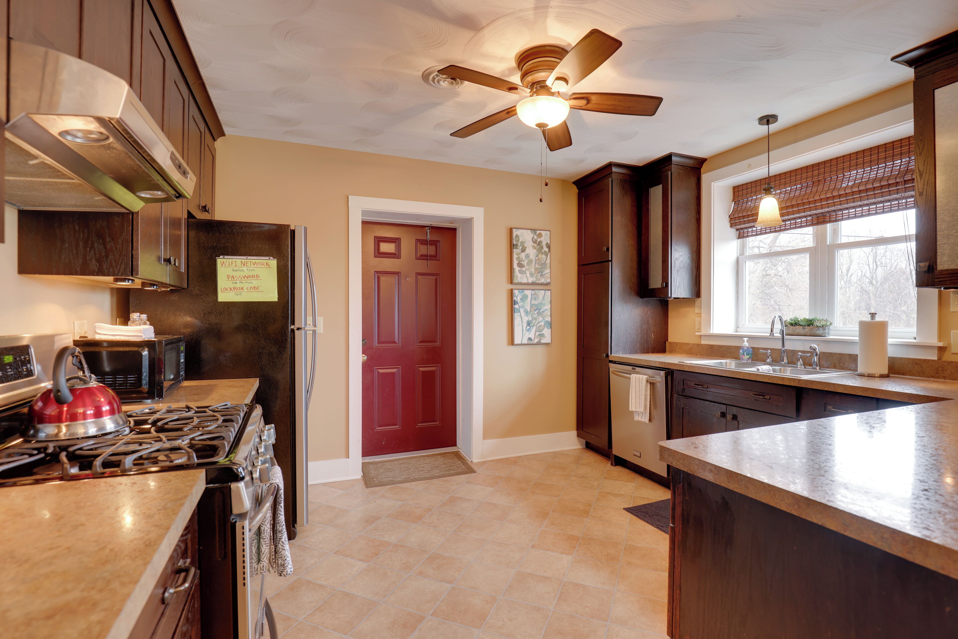 A kitchen with a stove, microwave, refrigerator, and a ceiling fan.