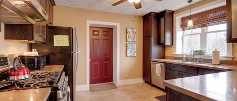 A kitchen with a stove, microwave, refrigerator, and a ceiling fan.