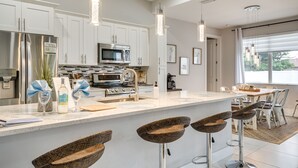 A modern kitchen with white cabinets, stainless steel appliances, and a central island with bar stools.
