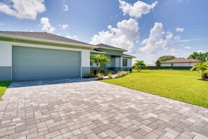 Une propriété résidentielle dotée d’une allée pavée, d’un garage et d’une pelouse bien entretenue.