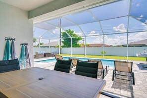 Un patio couvert avec une piscine, des sièges d’extérieur et une table.