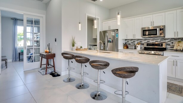 A modern kitchen with white cabinets, stainless steel appliances, and a central island with stools.