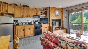 Una cocina con armarios de madera, microondas, lavavajillas y televisor.