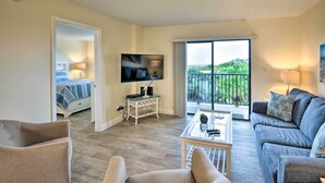 A hotel room with a balcony, a TV, a sofa, and a coffee table. - Sun-soaked Condo w/ Balcony - Steps to Beach! (Ormond Beach)