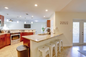 A modern kitchen with granite countertops, stainless steel appliances, and a central island with bar stools.