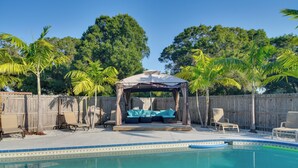 Piscina com área de estar coberta e espreguiçadeiras.