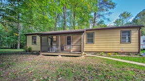 A single-story house with a covered porch, a small front yard, and a wooded backdrop. - Quaint Hinton Hideaway - Hunt & Fish Nearby! (Hinton)