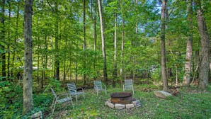 A forested area with a fire pit and metal chairs. - Quaint Hinton Hideaway - Hunt & Fish Nearby! (Hinton)