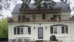 Une maison à deux étages avec un porche à l’avant, une terrasse couverte et un espace barbecue.