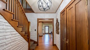 Un escalier en bois mène à une pièce dont un mur est en briques blanches et qui possède une porte en bois.