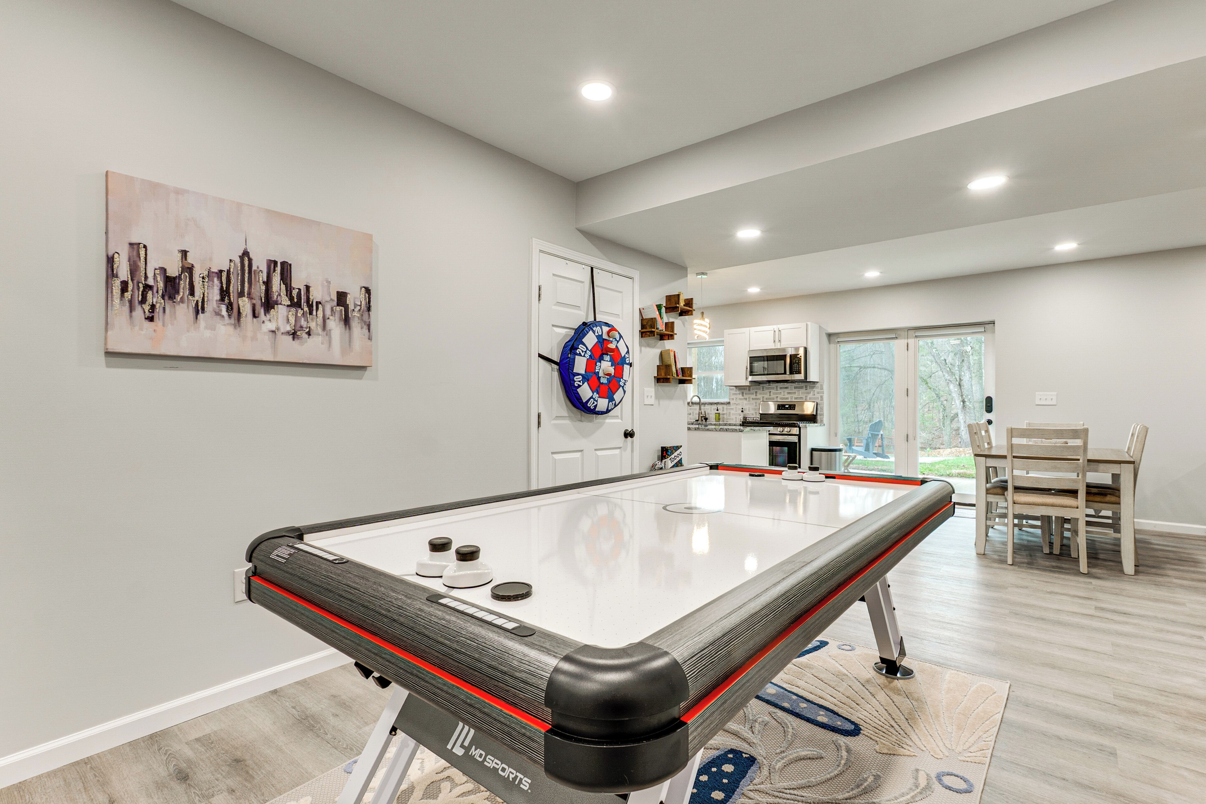 A modern indoor pool table with a dartboard and a cityscape painting on the wall.