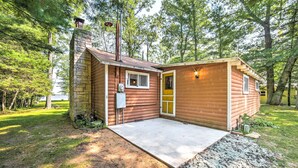 A small cabin with a stone chimney, a wooden door, and a concrete porch. - Crivitz Lakefront Escape w/ Boat Dock & Slip! (Crivitz)