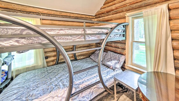 A bunk bed room with a wooden log wall, a window with curtains, and a small table. - Crivitz Lakefront Escape w/ Boat Dock & Slip! (Crivitz)