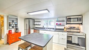 A modern kitchen with white cabinets, stainless steel appliances, a wooden table, and a red cabinet. - Crivitz Lakefront Escape w/ Boat Dock & Slip! (Crivitz)