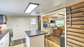 A modern kitchen with white cabinetry, a central island, and a dining area with a wooden accent wall. - Crivitz Lakefront Escape w/ Boat Dock & Slip! (Crivitz)