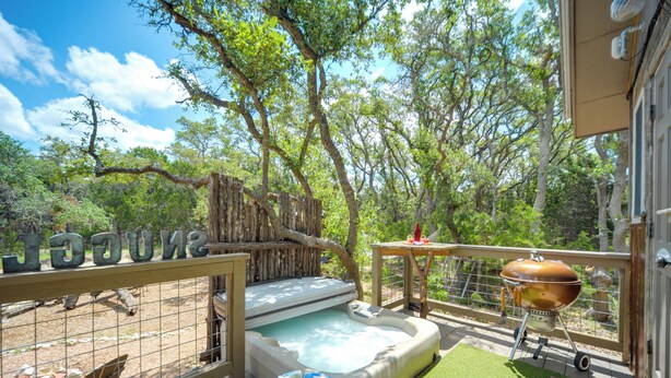A hot tub, barbecue grill, and a fenced area with a wooden deck.