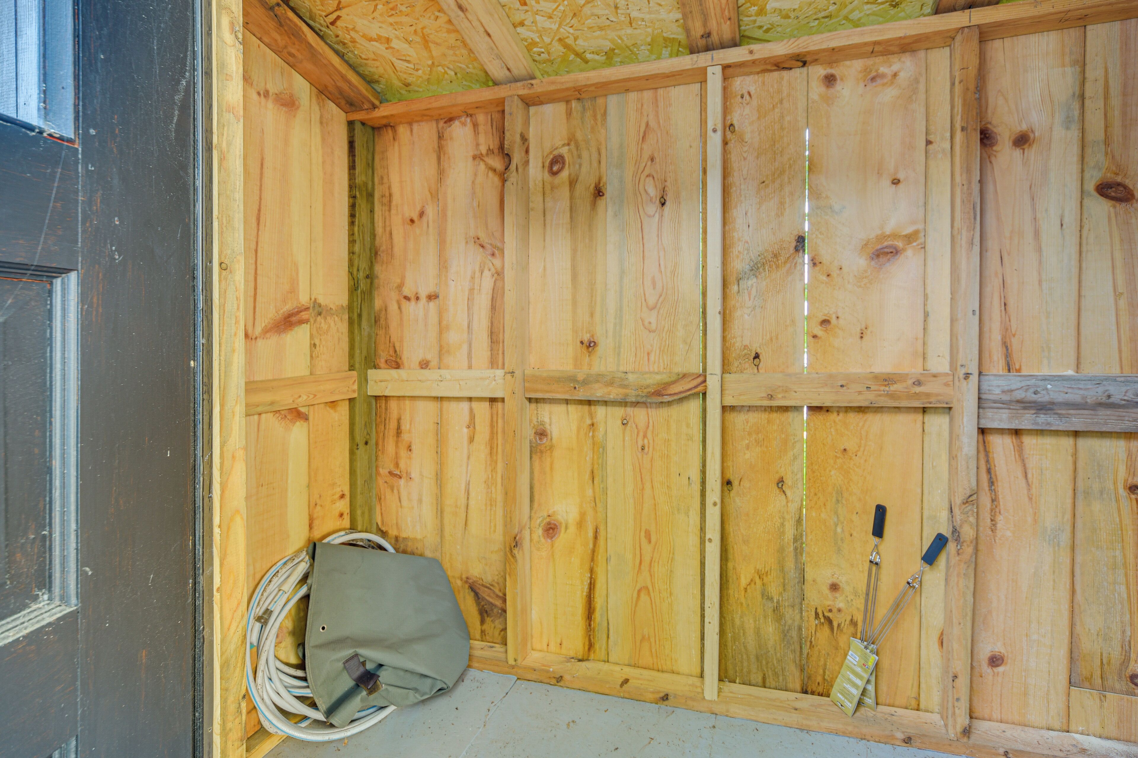 Ein Zimmer aus Holz mit Fenster, einem aufgehängten Mantel und einer Werkzeugkiste.