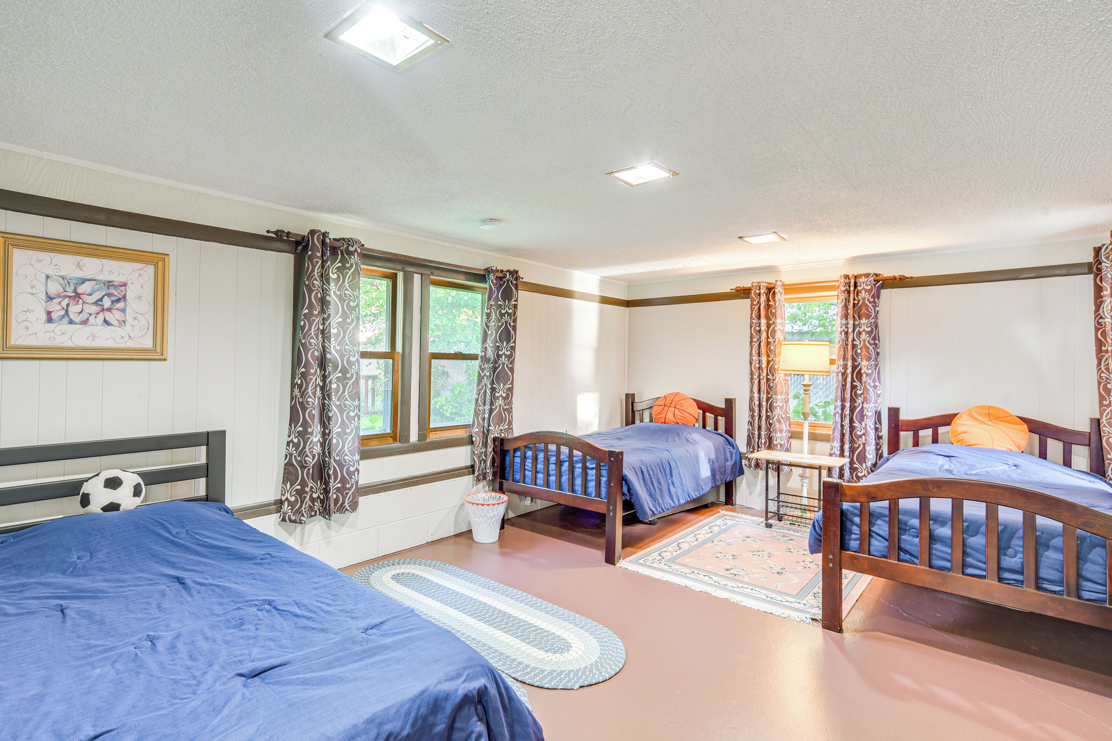 A room with three beds, a small table, and a window with curtains.