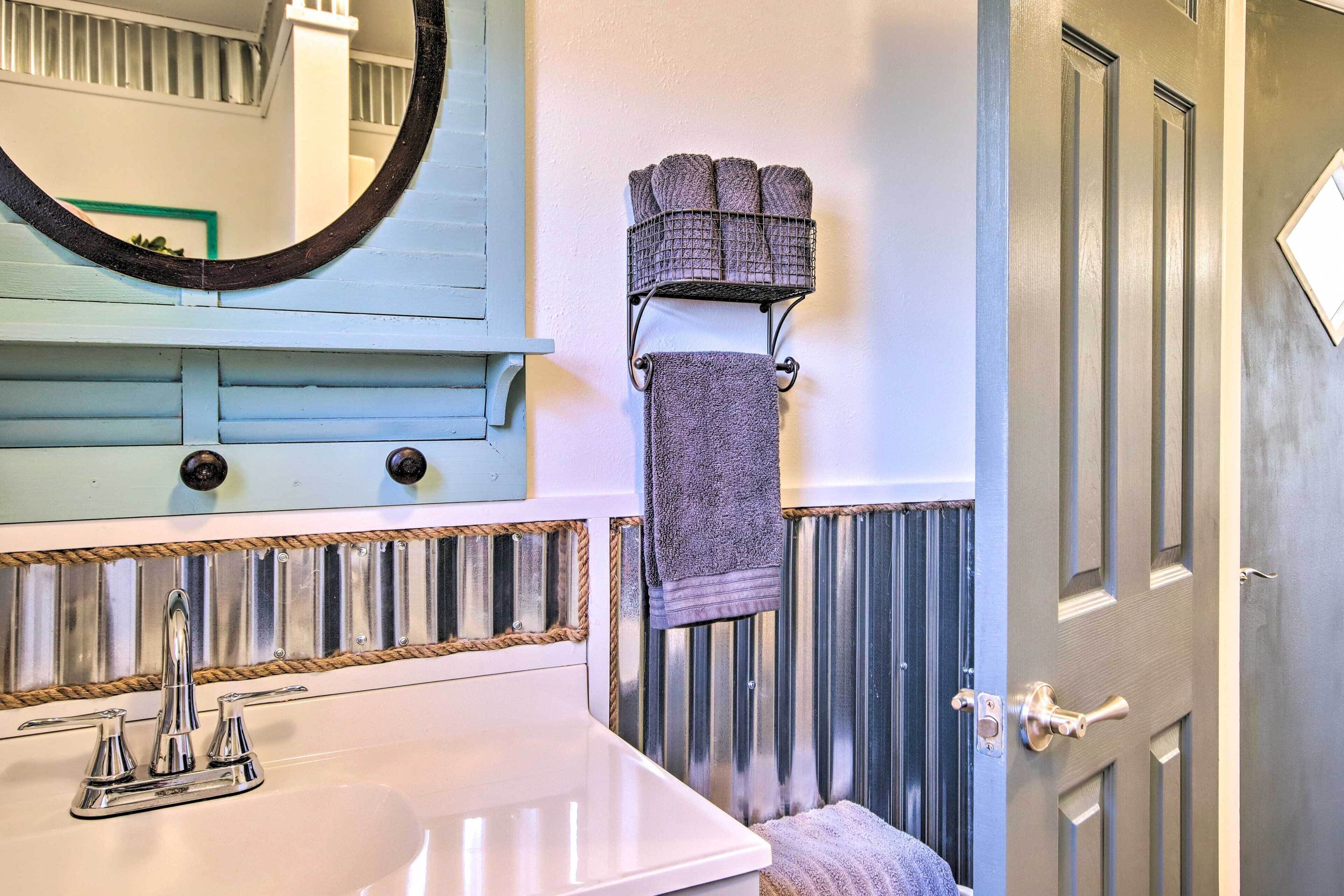A bathroom with a white sink, a mirror, and a towel rack with folded towels.