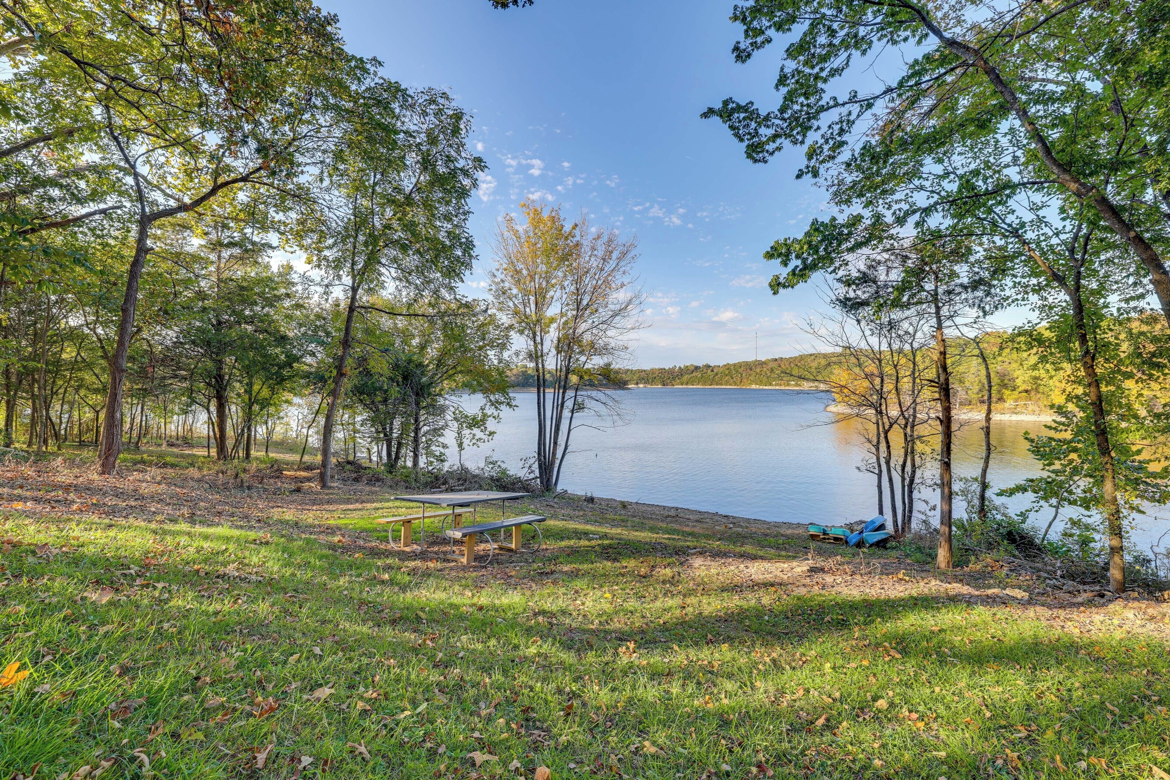 Un parque junto al lago con una mesa de picnic y bancos.